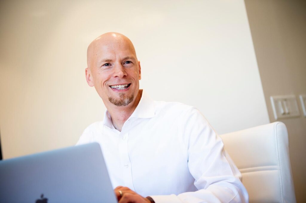 Dan Minior behind a laptop Raleigh skin health experts